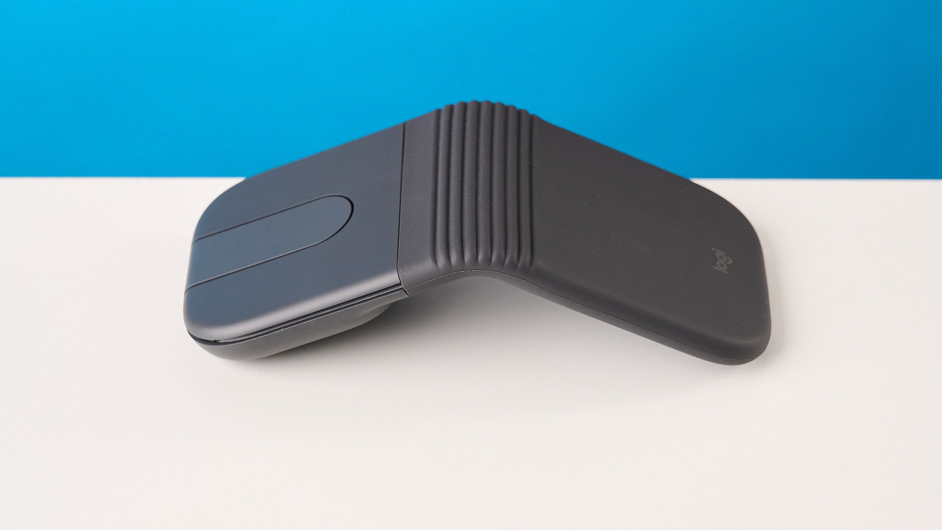 Logitech Mobi Fold mouse in graphite photographed in front of a blue background