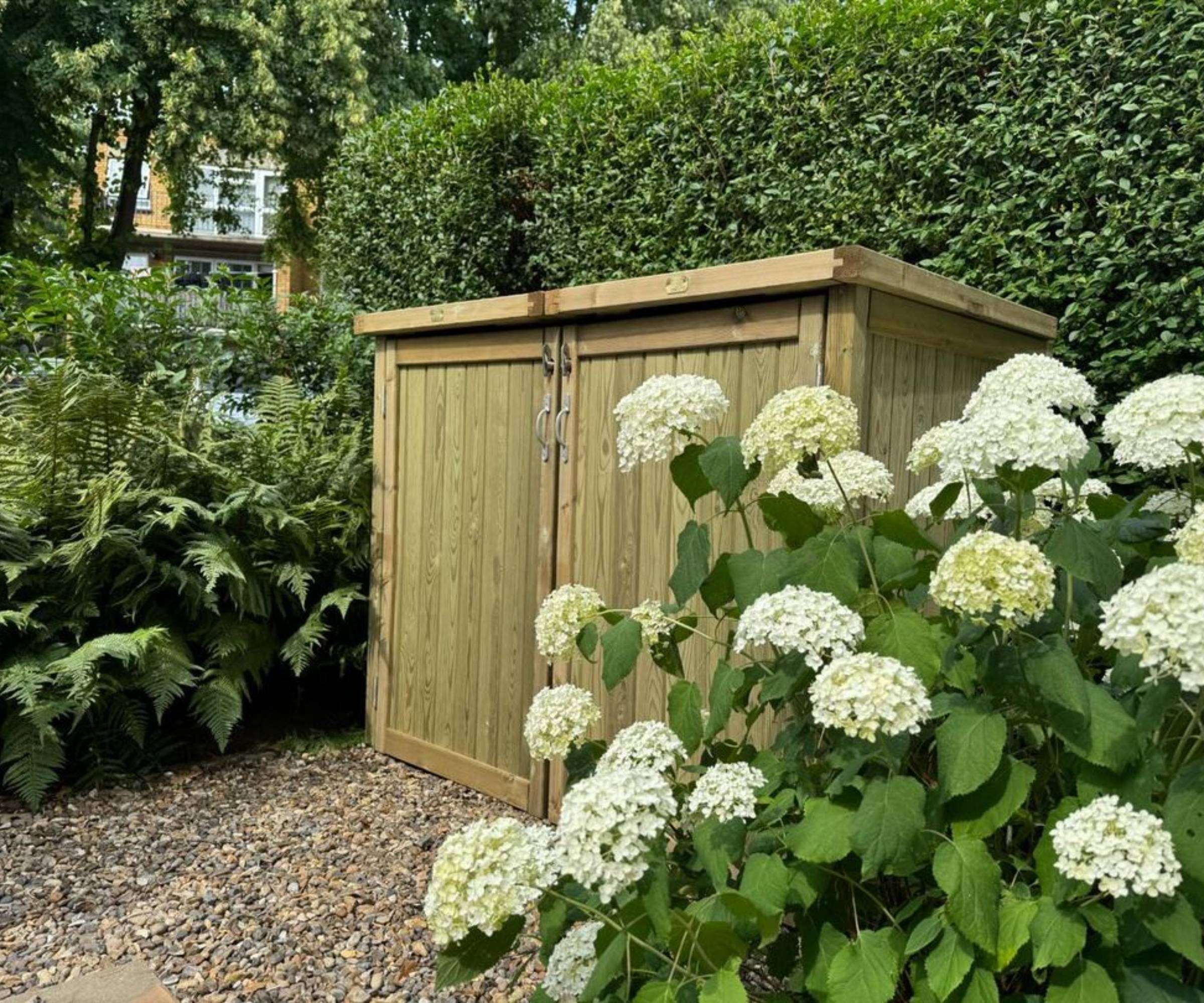 Timber wheelie bin store in garden next to hydrangeas