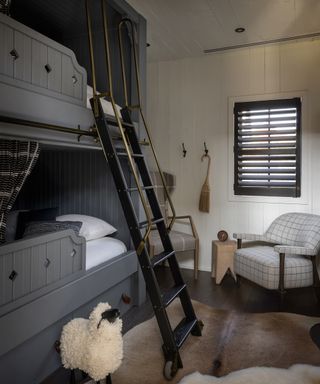 A bunk bed room with grey beds and black steps with a brass handle