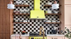 a black and white checkerboard kitchen backsplash with open shelving and a bright yellow extraction fan and stove.