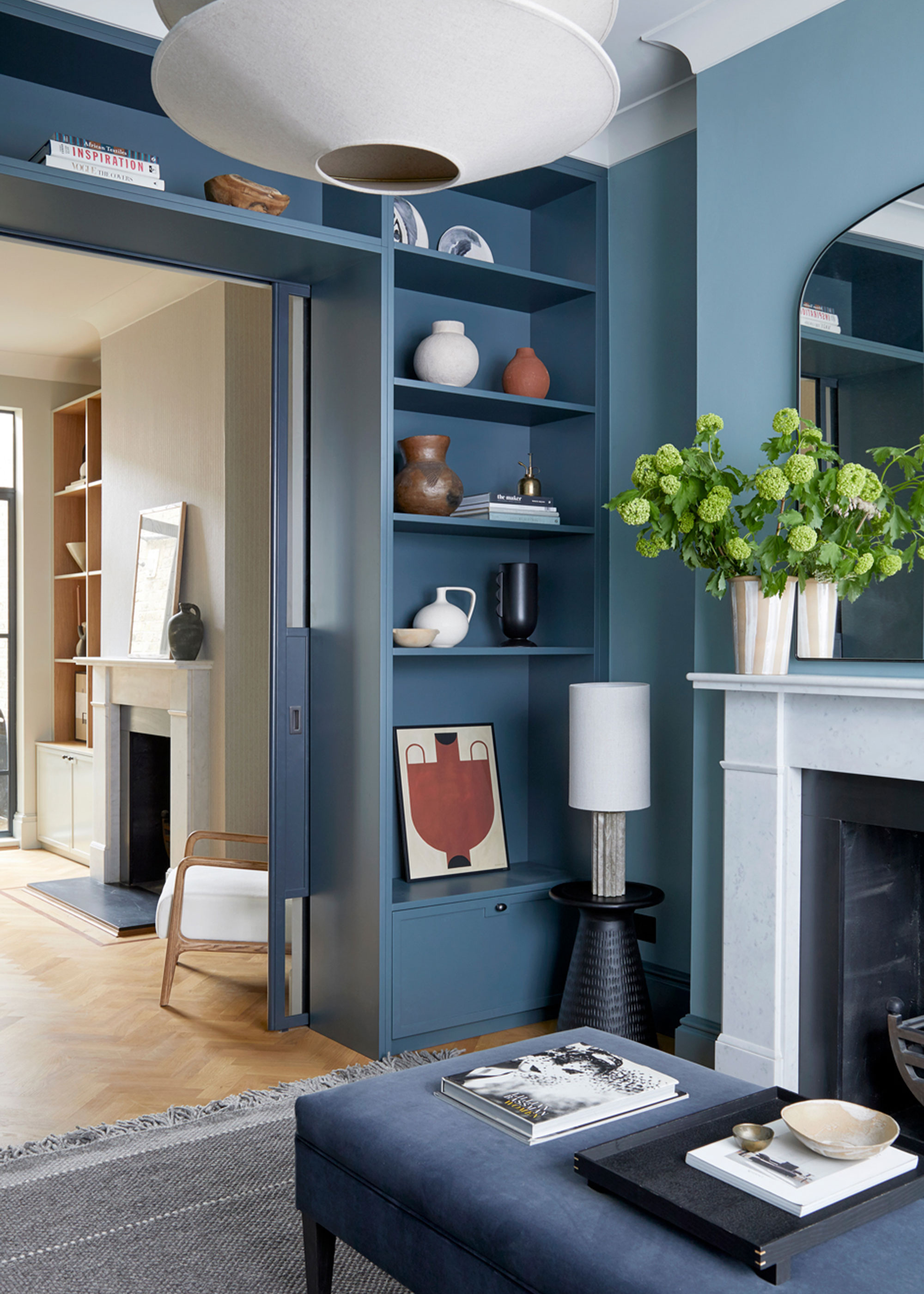 built-in alcove shelving that carries on across the top of the doorway painted in a dark blue and filled with decorative items in a living room space