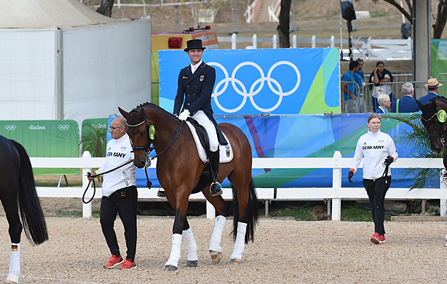 Groom Robbie Sanderson leading Cosmo in to the team dressage medal ceremony