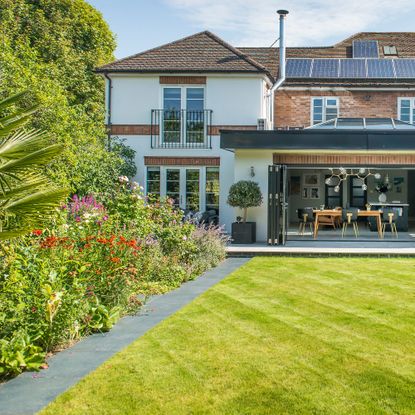 a garden with a large, perfectly kept lawn and lots of prairie-style flower planting in the borders