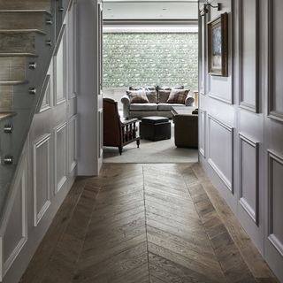 Hallway with sage green walls and chevron wood flooring