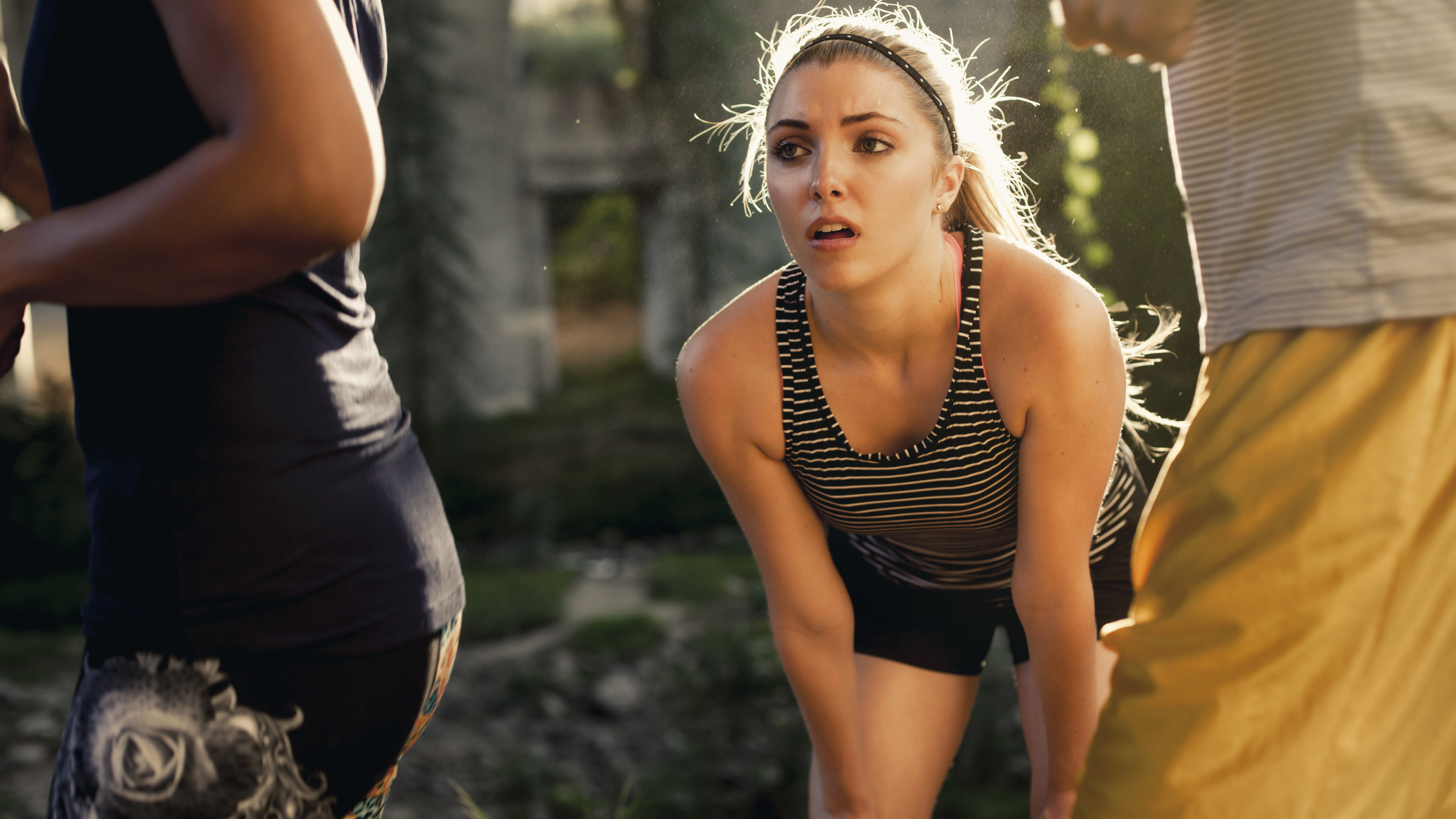 Runner resting with hands on knees as other runners pass her