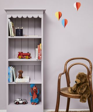 A baby girl nursery idea with walls painted in Lavender Garden from Mylands and shelving with toys and books.