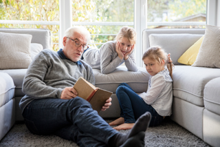 grandparent reading a book to two grandchildren