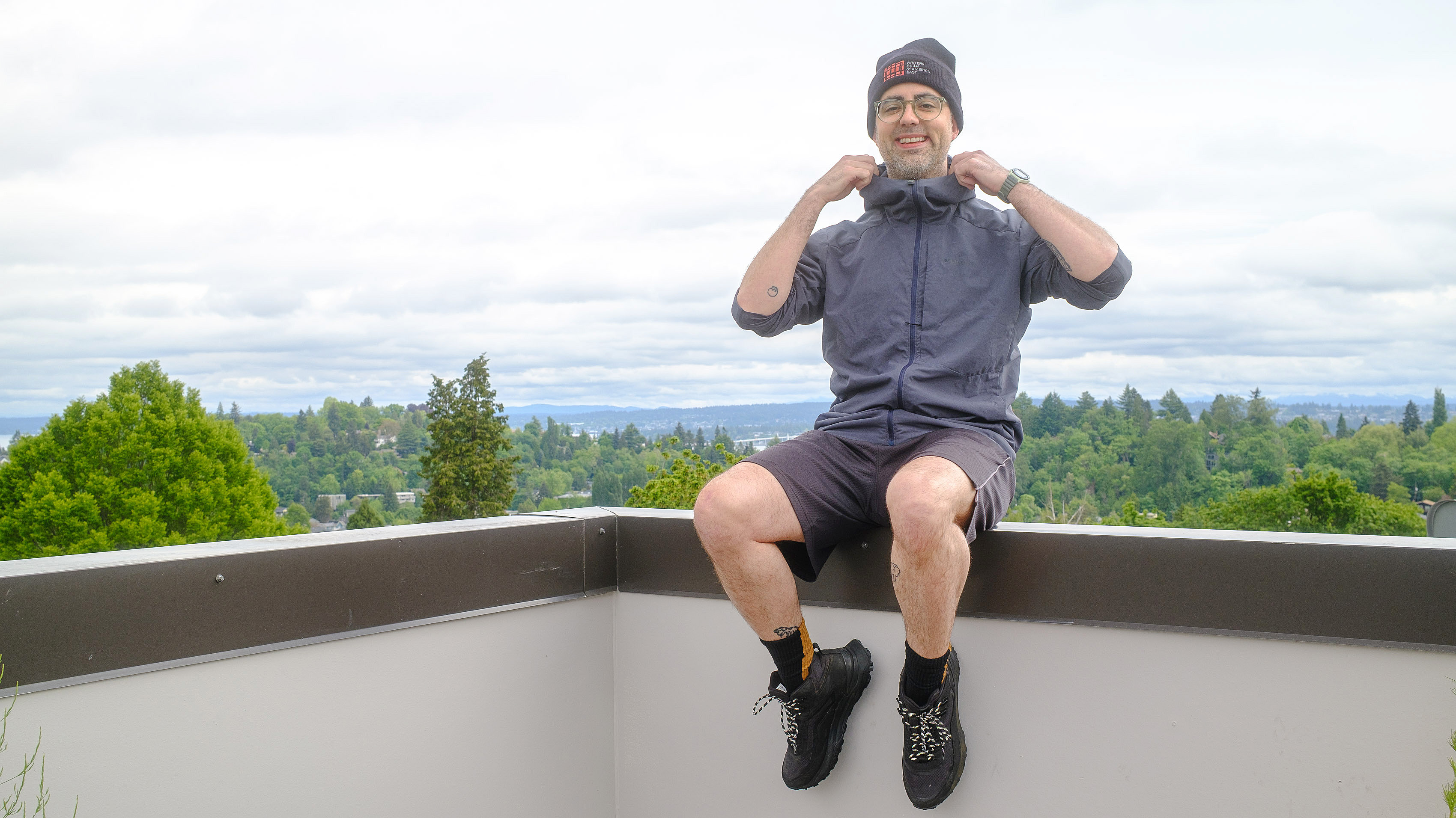 Senior writer Dan Bracaglia wearing the Patagonia Nano-Air Ultralight in grey/blue on the roof of his home in Seattle, Washington with trees and overcast skies in the distance
