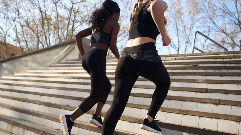 Two sportswomen during workout on stairs in leggings
