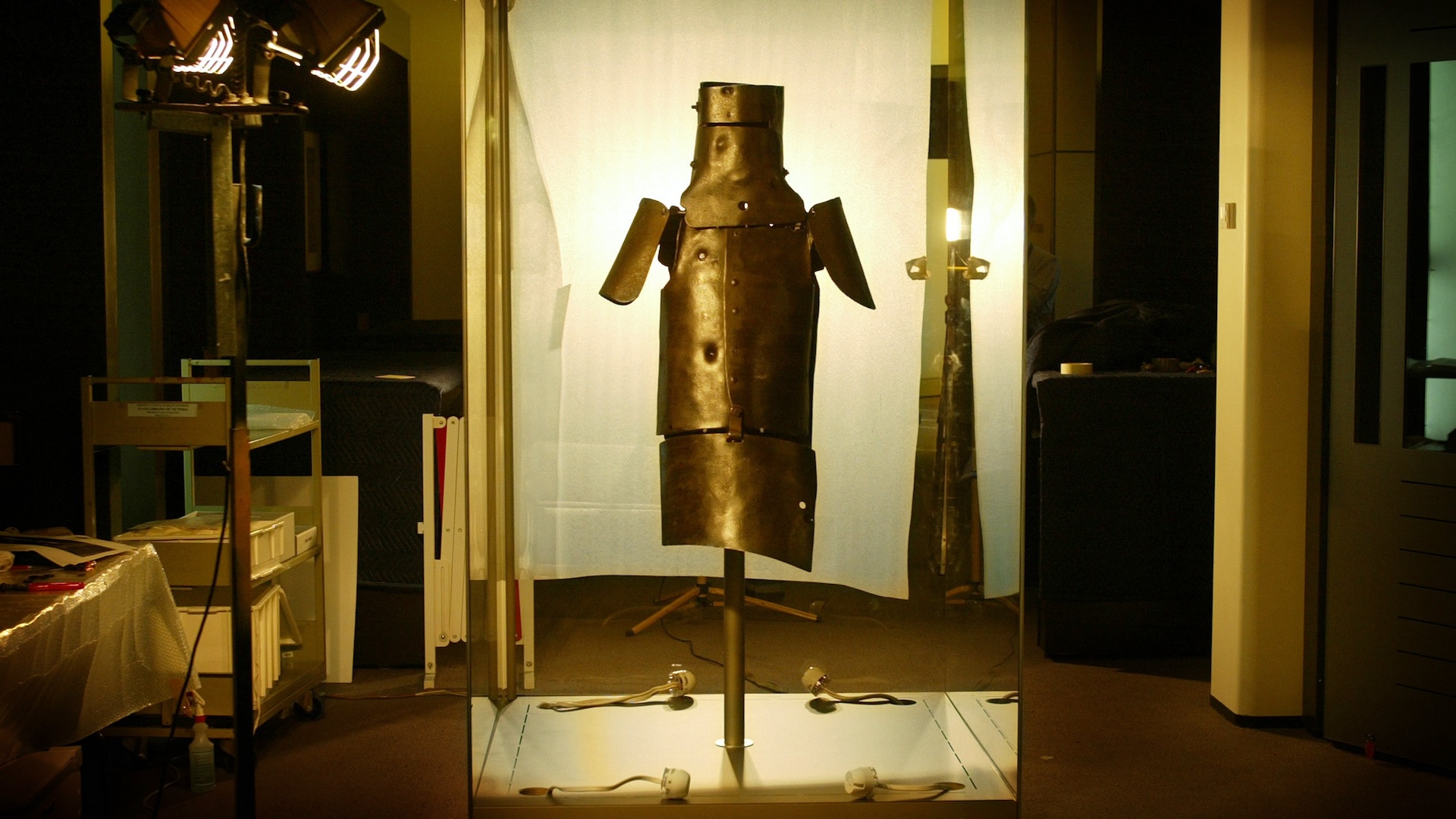 A simple set of armor is illuminated by lights in a dark room