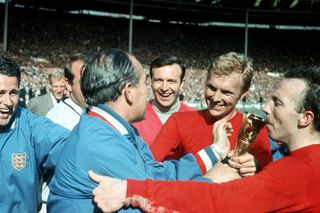 Stiles kisses the World Cup trophy, held by Sir Alf Ramsey