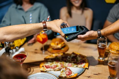 Young man paying the bill and tipping via contactless channel 