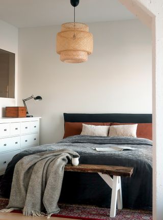 A simple bed with a rattan hanging light
