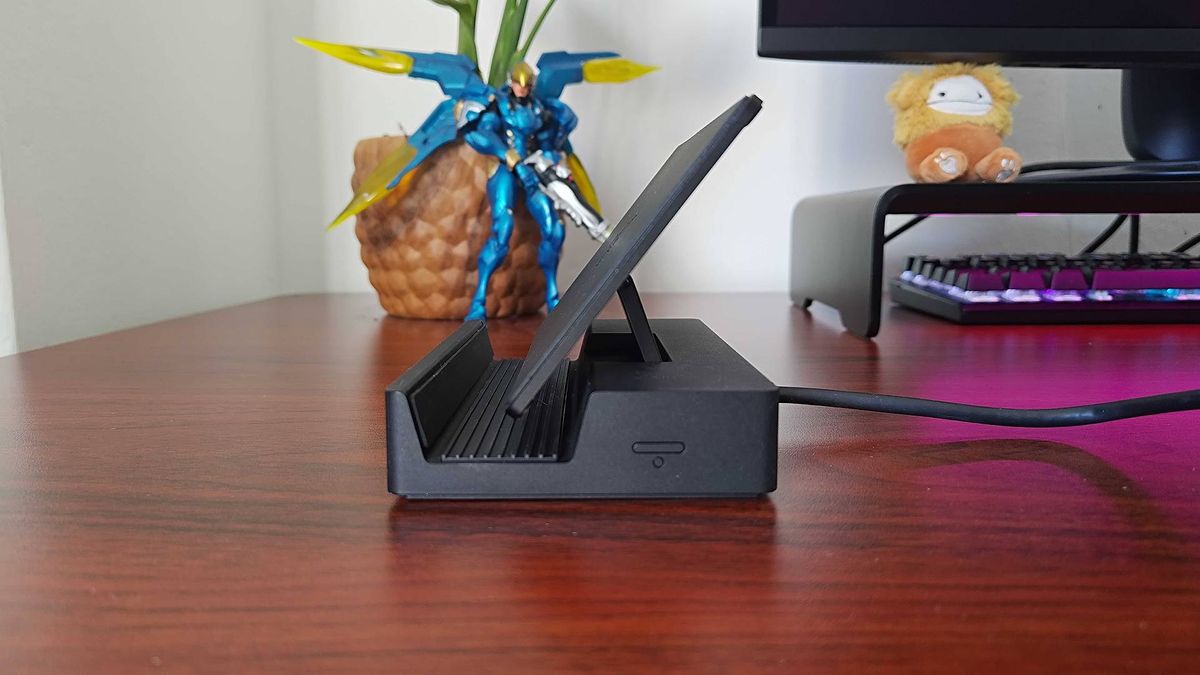 Side view of Razer Handheld Dock with cradle flipped up sitting on woodgrain desk.
