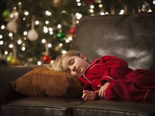 girl sleeping on the couch by the christmas tree