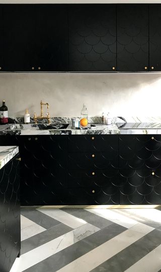 black kitchen cupboards with marble worktops and funky geometric flooring
