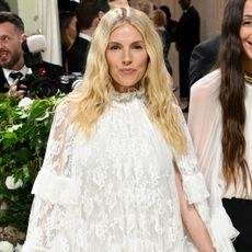 Sienna Miller wears a white lace dress Chloé dress and black studded shoes to the Met Gala 2024