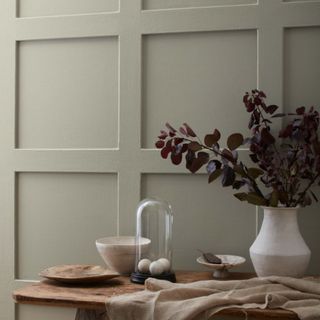 A light green paneled wall with a wooden table with kitchen accessories