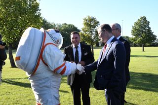 NASA Administrator Jim Bridenstine (right, foreground) shakes hands with a spacesuited subject during a tour of the University of North Dakota on Sept. 4, 2019. The NASA-funded UND spacesuit research is conducted under professor Pablo de Leon (center). At right, background, is North Dakota senator Kevin Cramer.