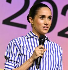 Meghan Markle wearing a blue and white striped top speaking in a mic