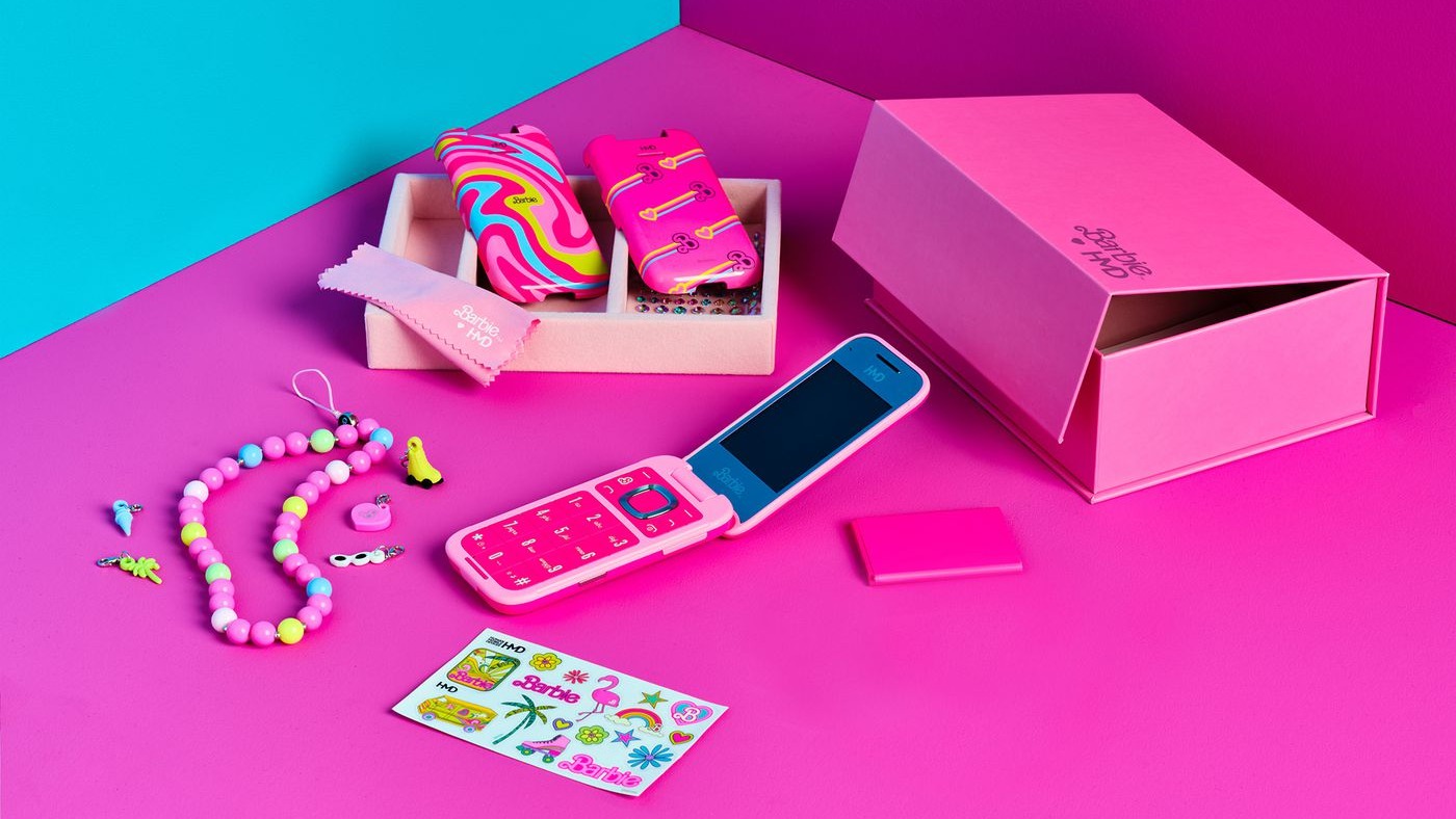 Barbie flip phone and accessories on a pink table