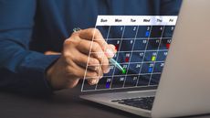 A man uses a digital calendar that appears to be floating above his laptop keyboard.