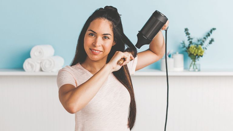 Woman using the shark hair dryer to dry her hair