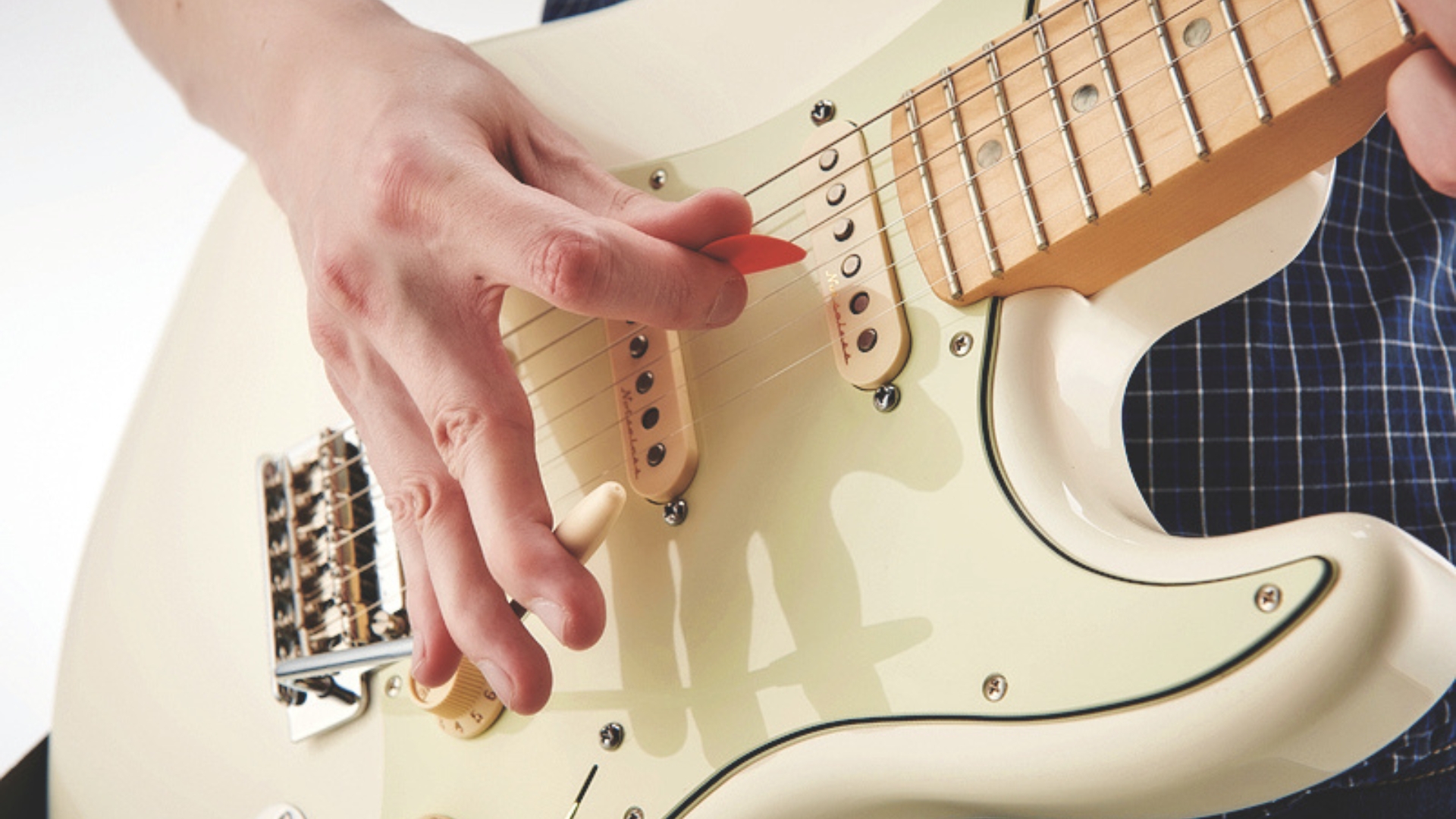 A man plays electric guitar with a guitar pick and uses the whammy bar