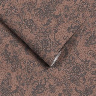 A close up shot of Woodchip & Magnolia Heirloom Lace Chocolate Wallpaper, which is brown with a black lace overlay