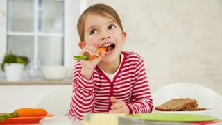 Health benefits of carrots: a young girl eats a carrot, which help promote good oral health