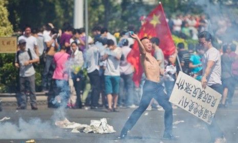 An anti-Japanese protester in Shenzhen, China throws a gas cannister as hundreds of people demonstrate over the disputed Diaoyu Islands. 