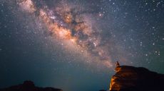 Silhouette man sits on the top of rock looking at the beautiful Milky Way Stars at the Grand Canyon of Thailand (Sam Phan Bok)