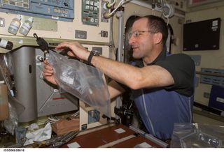On board the International Space Station, Expedition Six flight engineer Donald Pettit uses a chemical/microbial analysis bag to collect water samples from the Potable Water Heater in Russia's Zvezda Service Module.
