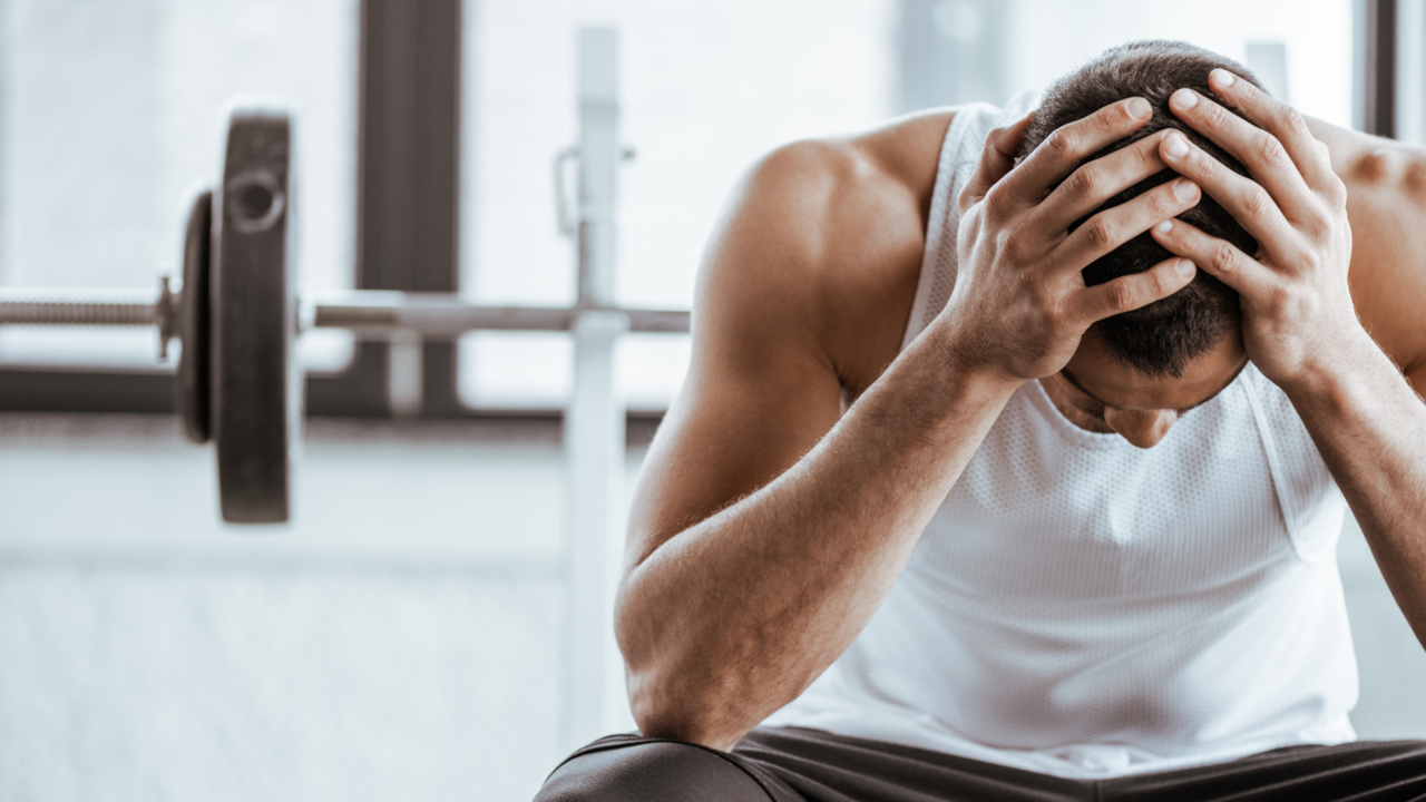 Man holding head in hands at the gym