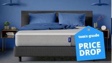 The Casper Mattress shown on a grey bed frame in a blue bedroom, with a blue price drop mattress sale badge overlaid on the image