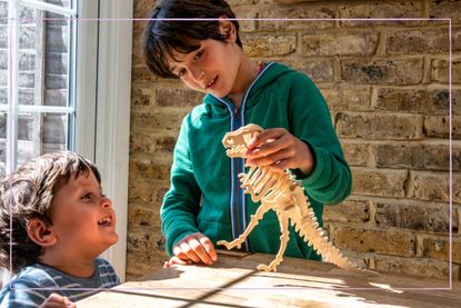 two boys playing with dinosaur model