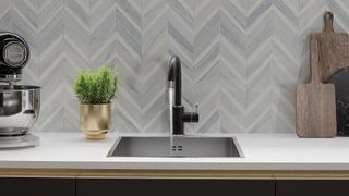 Contemporary stainless steel sink with a backdrop of herringbone style tiles