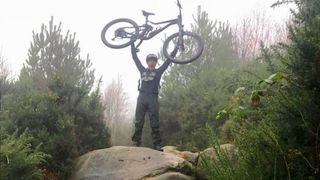 Mountain biker holding bike aloft
