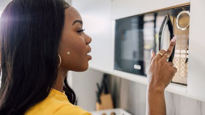 Woman pressing button on a microwave