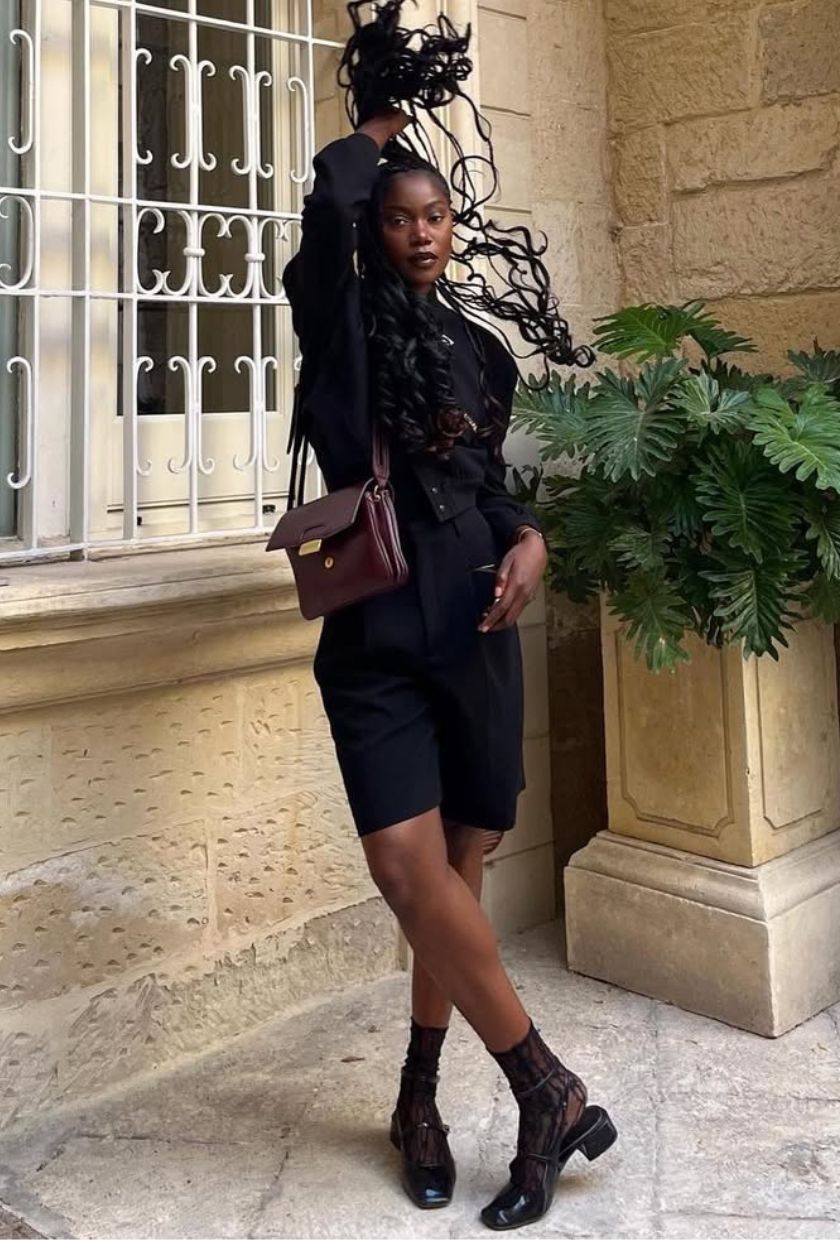 @andi_mun wears a black bomber jacket, Bermuda shorts, lace socks, Mary-Janes and a burgundy shoulder bag