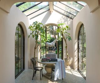 light conservatory room with light salmon walls, arched glass floor-to-ceiling windows and skylights