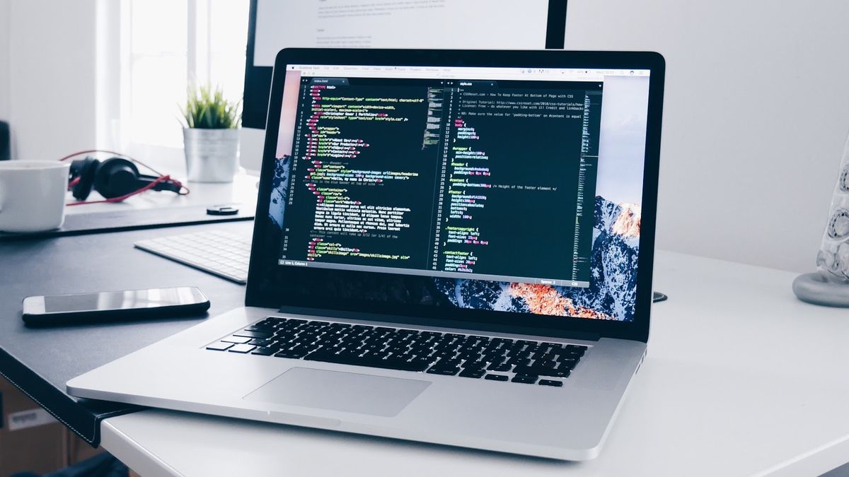 laptop on desk with coding displayed onscreen