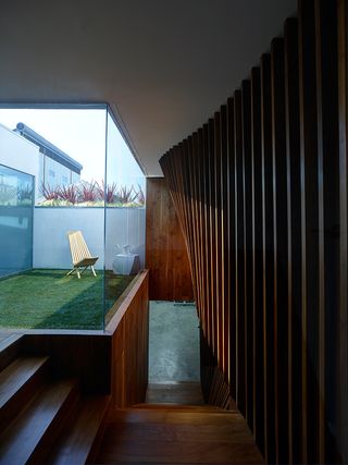 The walnut staircase leads to a glass-walled garden, with a Gehry ’Twist Cube’ stool