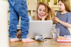 Young mother with a baby and a dog, sitting on the floor and working. High angle of view.