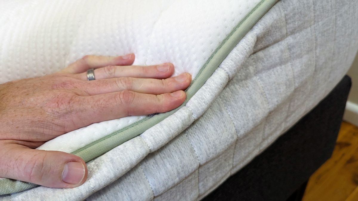 Hand pressing firmly down on side of Koala SE mattress, showing edge support