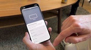 A man holding a phone with Sonos' new AI Speech Enhancement features shown on the screen