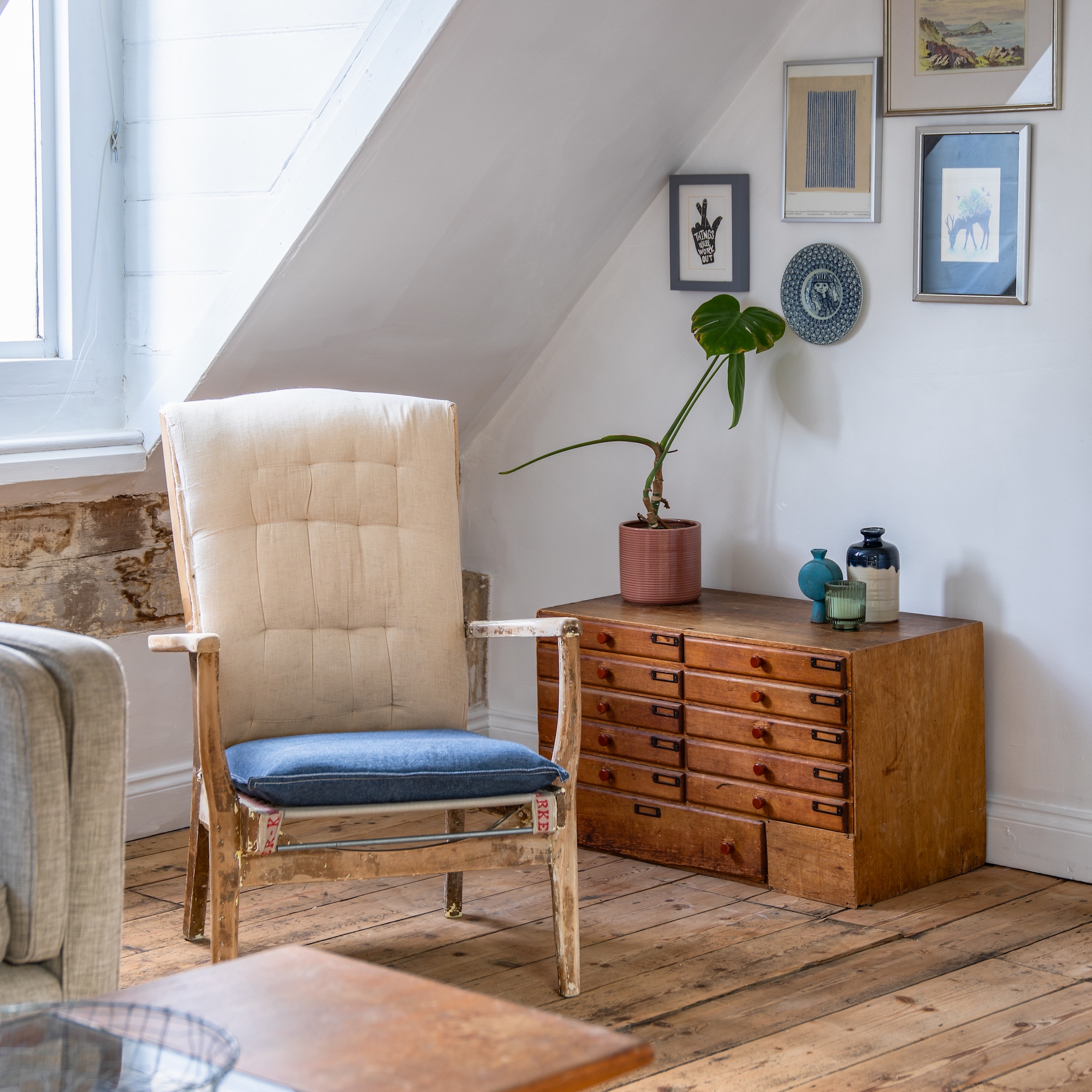 loft room with slanted ceiling and window decorated with vintage chair and plan chest