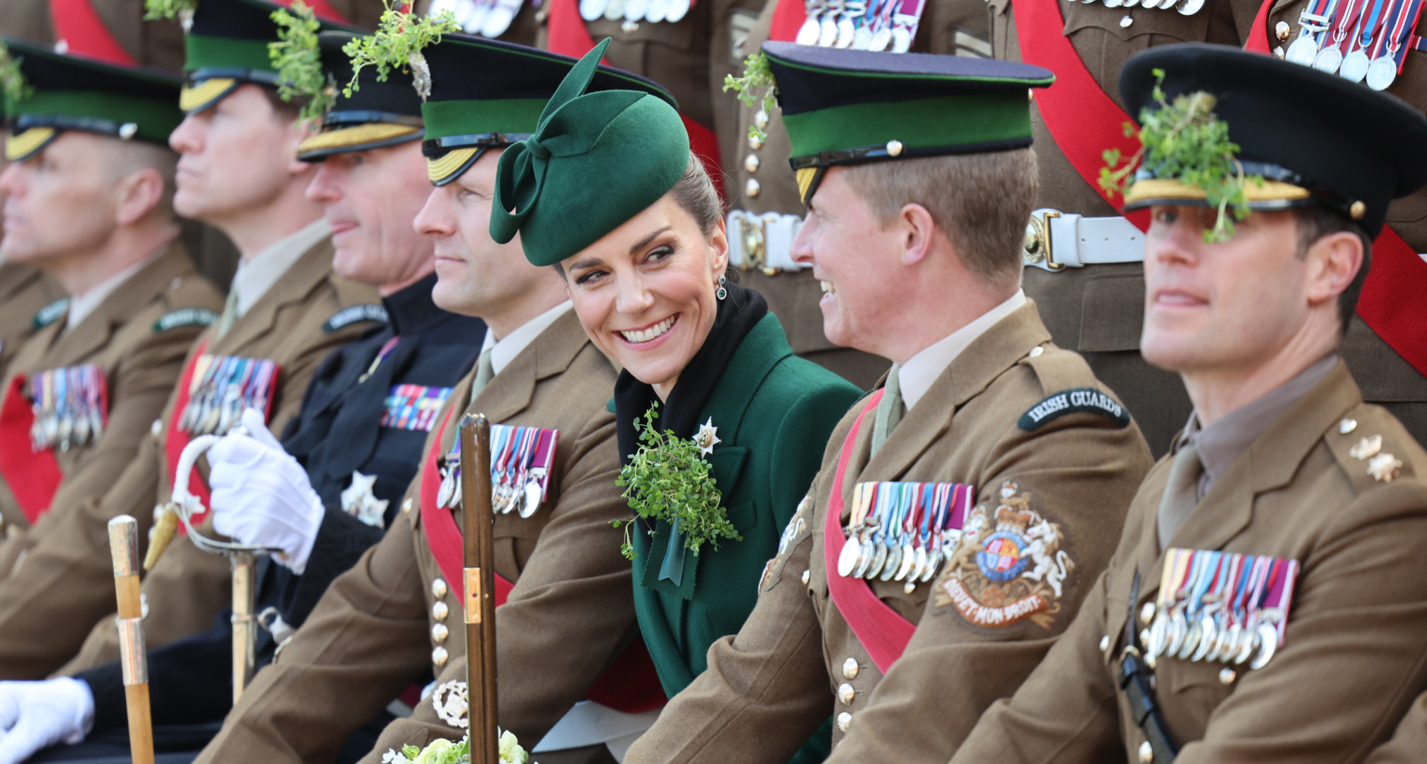Princess Kate wearing a green coat sitting in a row of uniformed soldiers
