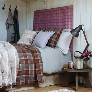 Tartan bedsheets and headboard in rustic looking bedroom