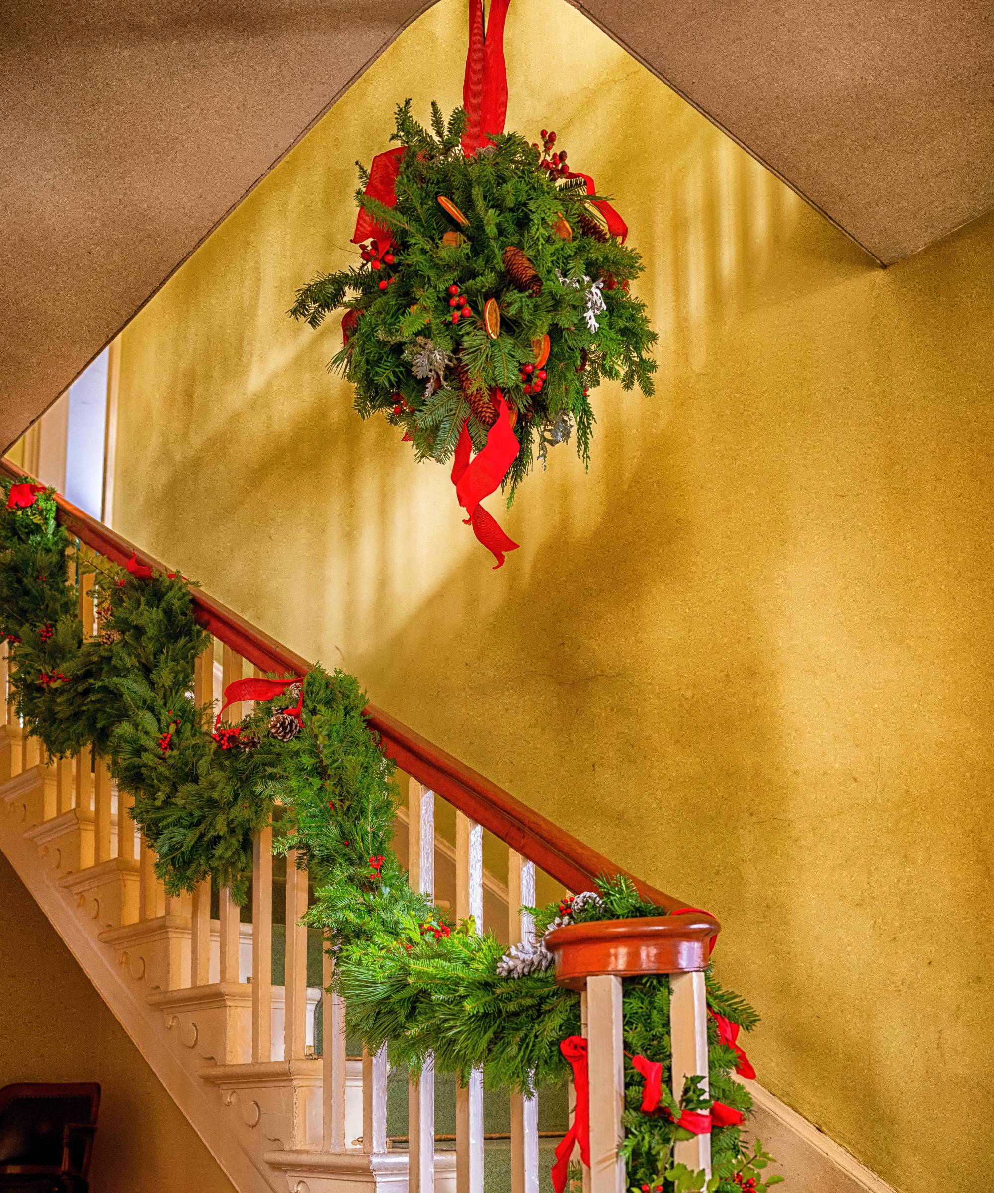 Kissing ball hanging in stairway with other Christmas greenery